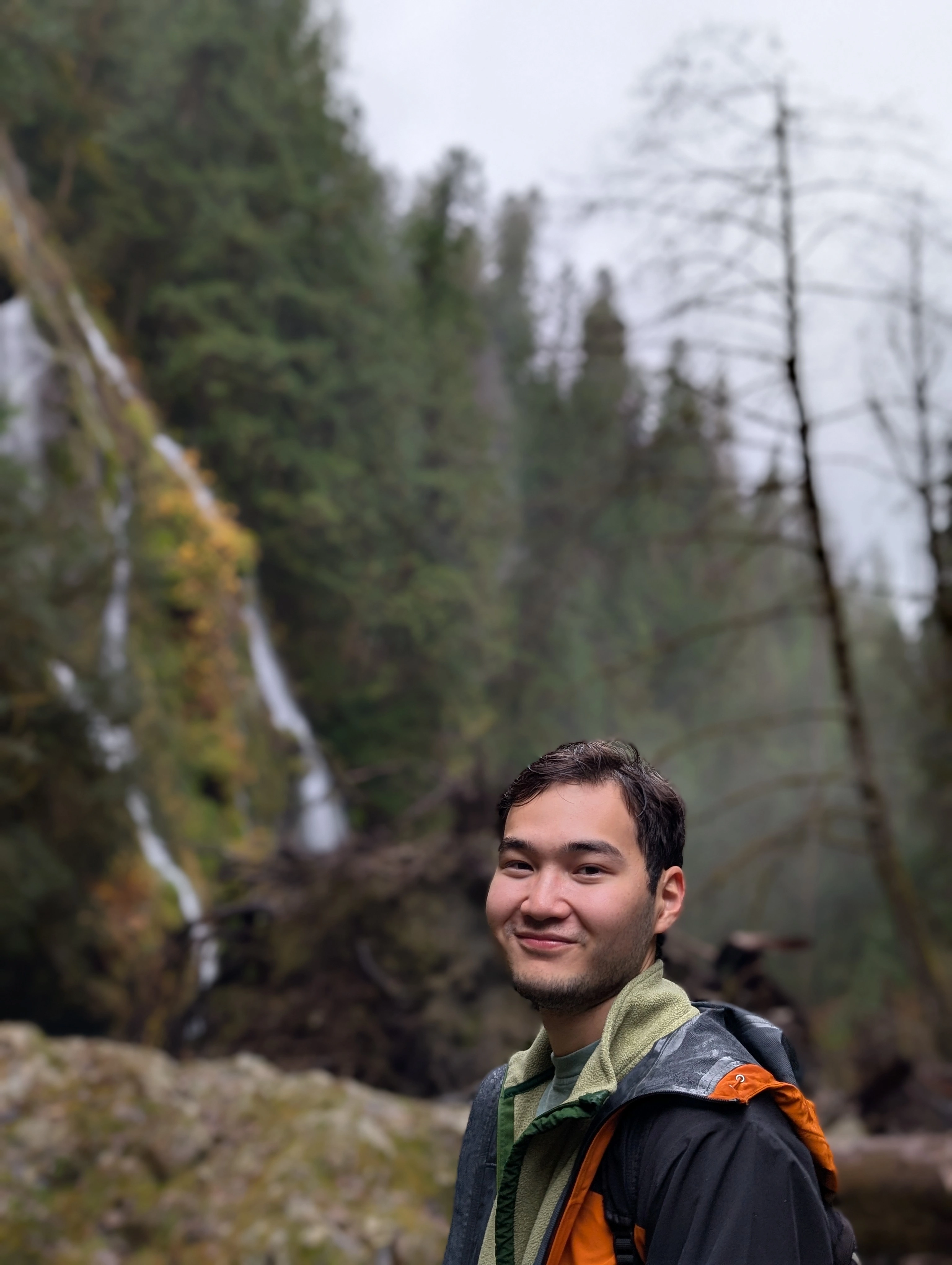 Abylay outdoors by a forest waterfall